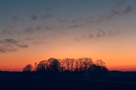 Sunset over a farmland with tree silhouettes ju8st before the sun is set