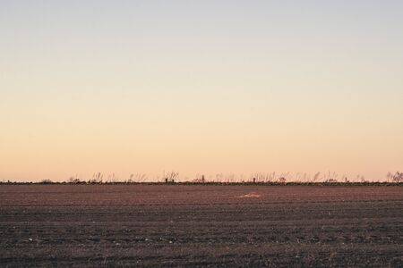 Plowed field in the sunset at dawn with a clear sky over a beautiful countryside