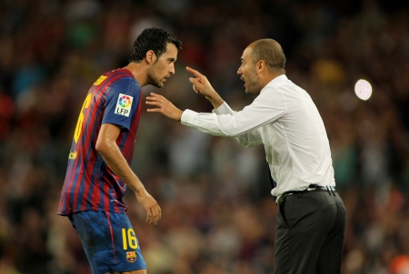 Guardiola trainer of FC Barcelona gives orders to Sergio Busquets during a Spanish League match against CF Villarreal at the Nou Camp Stadium on August 29, 2011 in Barcelona, Spainのeditorial素材