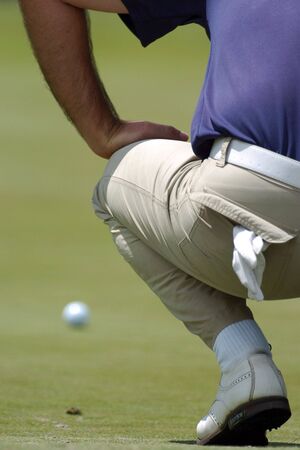 A golfer putts a ball on the green.の写真素材