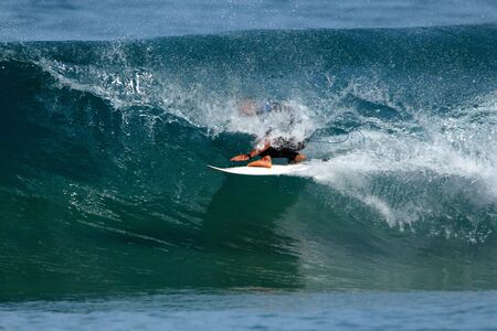 A male surfer gets barreled in a big wave.