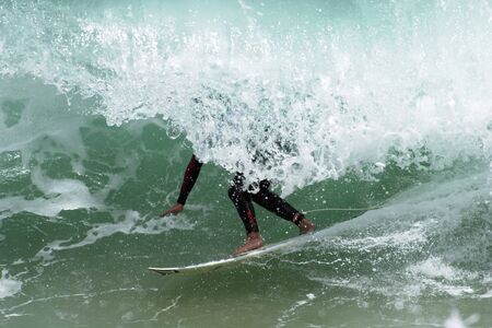 A surfer gets barrelled in a big wave.