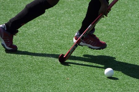 A field hockey player runs with the ball and stick.の写真素材