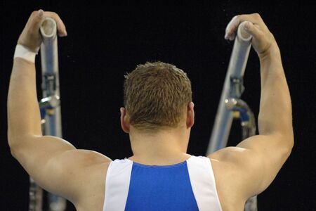 A male gymnast is about to preform a routine on the parallel bars during competition.の写真素材