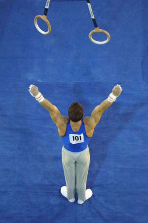 A male gymnast preforms a routine on the rings during competition.の写真素材