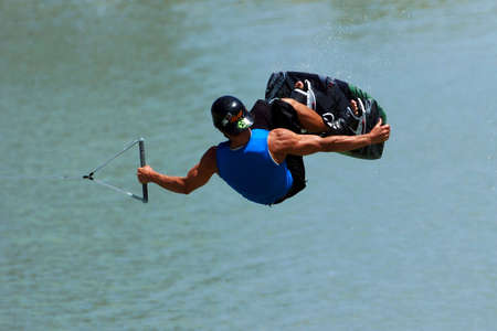 An extreme wakeboarder preforms a manouver in the air while grabbing his board.の写真素材