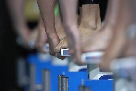 Toes and hands touch the blocks at the start of a swim race.の写真素材