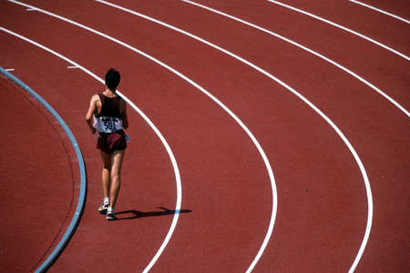 A lone runner or race walker along a bend on the track at athletics.の写真素材