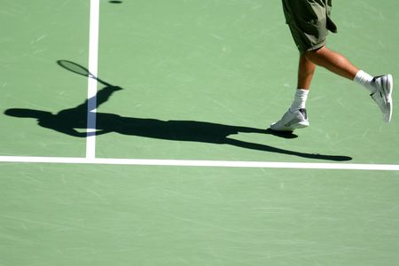The shadow of a man playing tennis on a court.の写真素材