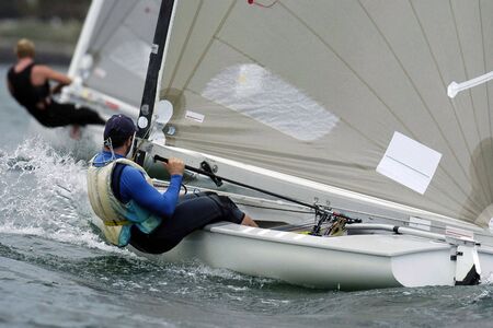 A Finn sailor crashes through a small wave during a race