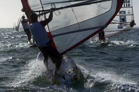 A sailboarder crashes through a small wave during a raceの写真素材