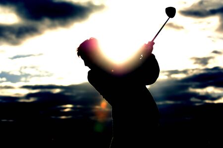 A left handed golfer tees off in the early morning light.の写真素材
