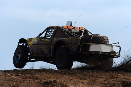 An off road buggie races through the mud during a competition.