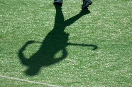 The shadow of a field hockey player as they run down the pitch during a competition.の写真素材