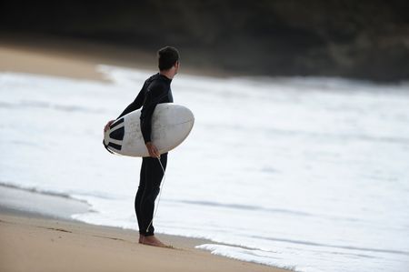 A male surfer checks the waves before heading out into the ocean.の写真素材
