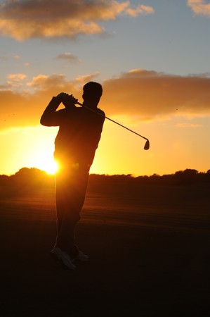 A male golfer enjoys an early round during sunrise. 
