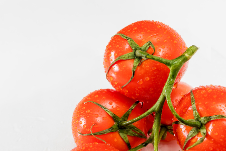 Tomatoes on a branch with droplets of water.の写真素材