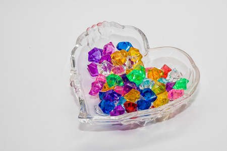Glass pebbles of different colors in a crystal vase on a white background.の写真素材