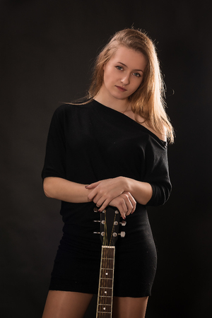 Beautiful girl with guitar on black background.の写真素材