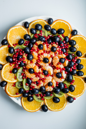 Fruit dessert. The cutting of the fruit. Orange, grapes, pomegranate. Festive table.の写真素材