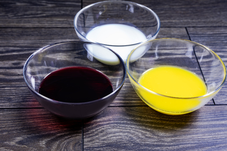Liquids of different colors in glass plates on a wooden table.の写真素材