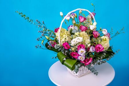 Beautiful bouquet of flowers on white round table on blue background.の写真素材