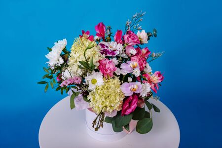 Beautiful bouquet of flowers on white round table on blue background.の写真素材