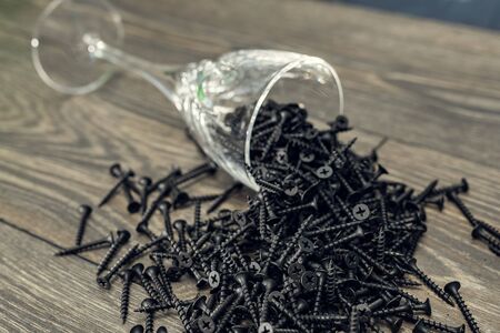 Pile of black screw nails on wooden background. Lots of screws on the table.の写真素材