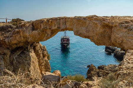The bridge of love or love bridge. Pirate ship sailing near famous Bridge of Love near Ayia Napa, Cyprus.の写真素材
