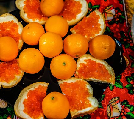 Sandwiches with red caviar and tangerines on a platter.