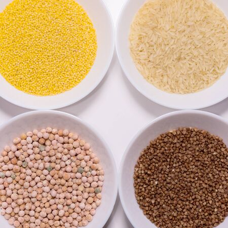 Various dry cereal and bean backgrounds: rice, peas, rice, buckwheat in white bowls. View from...