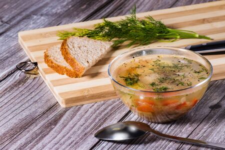 Dietary soup with chicken meatballs and green peas in a glass bowl on a wooden background. Top view.