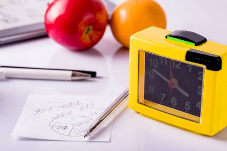 Office desk with pens, clock, note paper and tablet. Office supplies on a white background.の写真素材