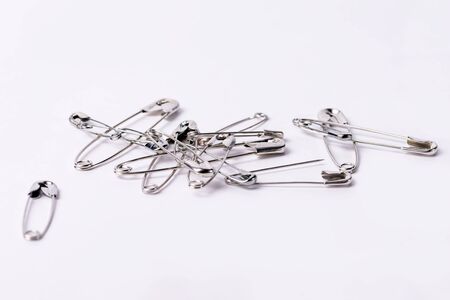 Collection of pins of different sizes on a white background. Various safety pins on the table.