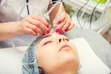   Beautiful young woman getting a facial massage with her eyes closed at the Spa. Various services...