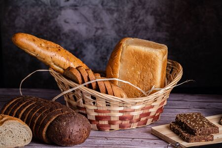 On a wooden table, bread of different varieties in a basket. Sliced bread for eating.