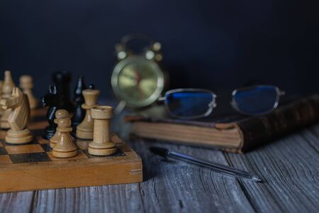 The glasses are on a stack of books. Chess is ready to start the game.の写真素材