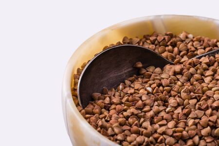 Raw dry buckwheat grain in a bowl with a spoon close up.の写真素材