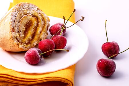 Roll with cream and cherries with berries on a white