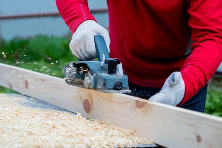 A man's hand holds an electric planing tool