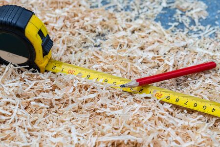 On the table in the sawdust tape measure and pencil.の写真素材