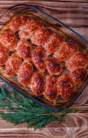 Fried meat cutlets were taken out of the oven on a baking tray on a wooden table.