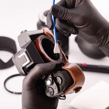A gloved photographer takes care of photographic equipment with special tools. The concept of a...