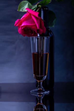 A bottle of wine with a beautiful glass and a beautiful rose on a dark background.の写真素材