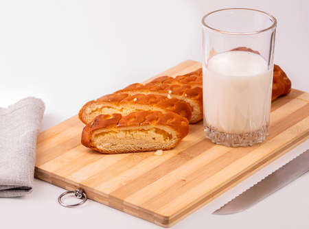 Delicious roll with cottage cheese on a wooden Board and a glass of milk.