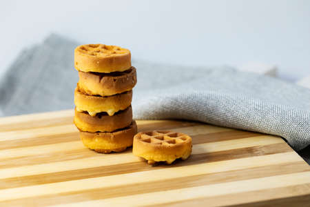 A stack of round little waffles on a wooden table.の写真素材