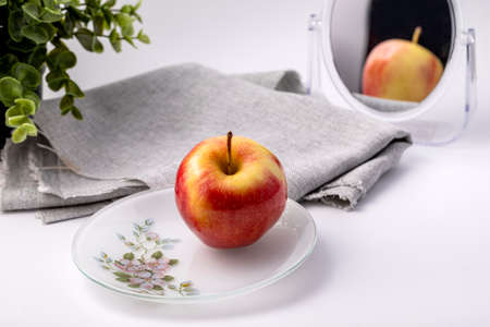 Red Apple on a white plate on a white table.の写真素材