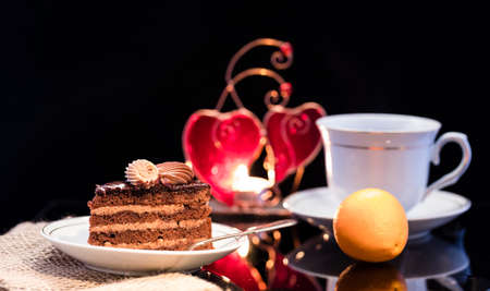 A piece of chocolate cake on a saucer on a black background. Delicious breakfast.Traditional...