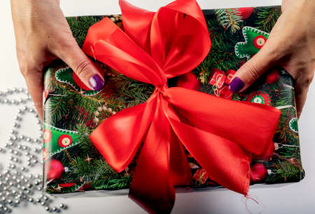 The girl unties the bow on the gift box. The concept of the new year holiday. The girl opens the gift.の写真素材
