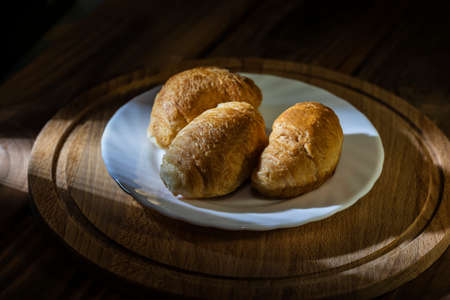 Croissants on a white plate on a wooden table in the morning light.
